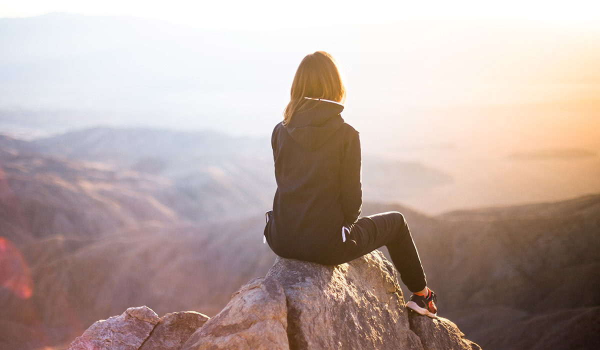 Woman sitting on mountain looking out over landscape